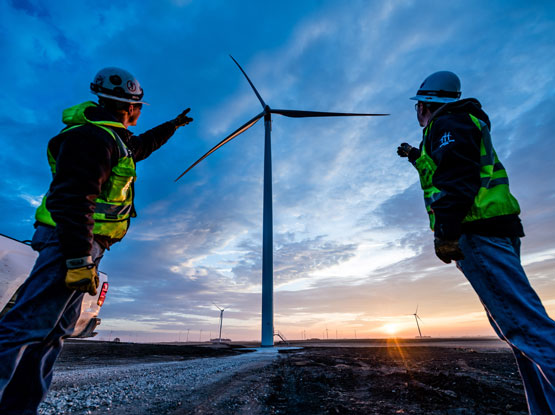 Construction team members pointing to wind turbine